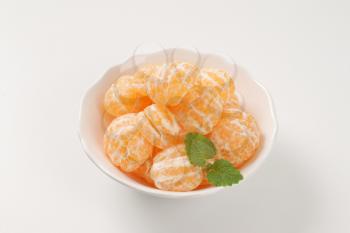 bowl of peeled tangerines on white background