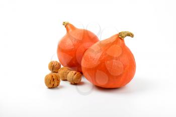 two orange pumpkins with walnuts on white background