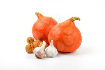 two orange pumpkins wtih garlic and walnuts on white background