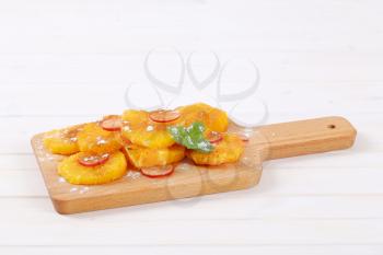 slices of orange and radish sprinkled with cinnamon on wooden cutting board