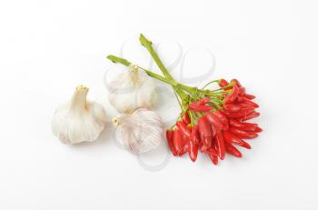 Bunch of small red chili peppers and garlic bulbs on white background