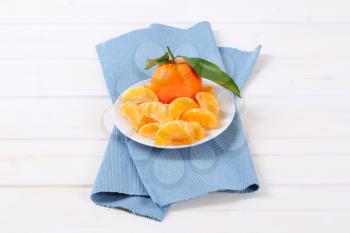 whole and peeled tangerines on white plate