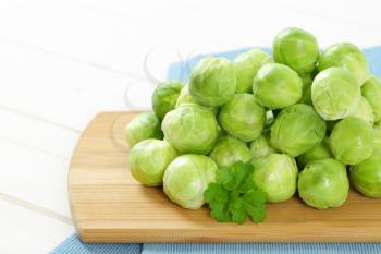 heap of raw Brussels sprouts on wooden cutting board - close up