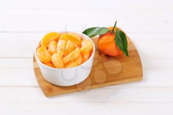 whole ripe tangerine with peeled slices in bowl