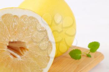 fresh ripe pomelo on wooden cutting board - close up