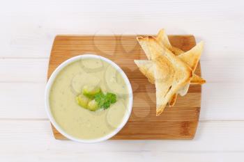 bowl of Brussels sprouts soup with toast on wooden cutting board