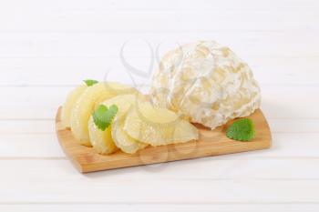 peeled and sliced pomelo on wooden cutting board
