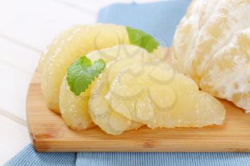 peeled and sliced pomelo on wooden cutting board - close up