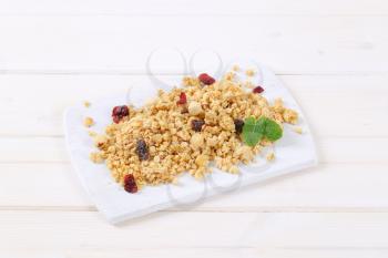 pile of morning granola with hazelnuts, raisins and cranberries on white cutting board