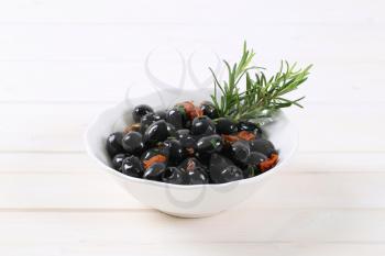 bowl of black olives with dried tomatoes on white background