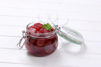 jar of sliced and pickled beetroot on white wooden background