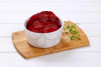 bowl of thin beetroot slices on wooden cutting board