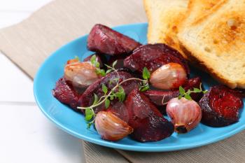 plate of baked beetroot and garlic with toasted bread - close up