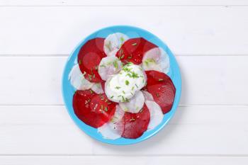 plate of thin beetroot and white radish slices on white wooden background