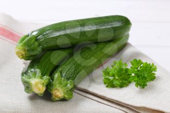 fresh green zucchini on folded dishtowel - close up