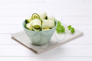 bowl of raw zucchini strips on beige place mat
