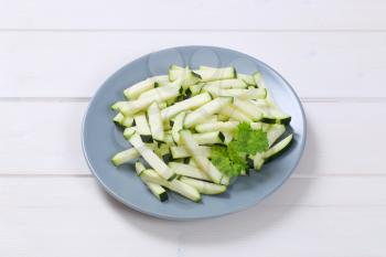 plate of zucchini strips on white wooden background