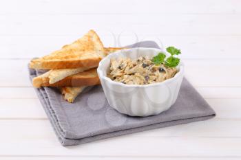 bowl of grated cheese spread with olives and toasted bread on grey place mat
