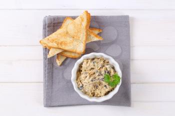 bowl of grated cheese spread with olives and toasted bread on grey place mat