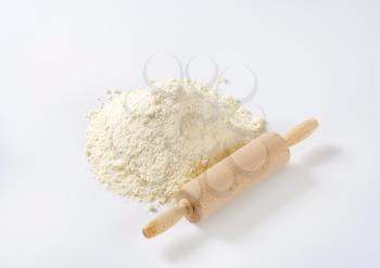 pile of wheat flour and wooden rolling pin on white background