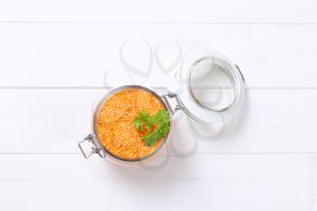 jar of peeled red lentils on white wooden background