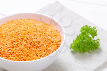 bowl of peeled red lentils on beige place mat - close up