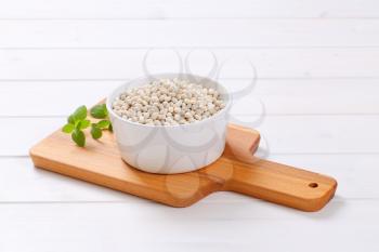 bowl of raw white beans on wooden cutting board