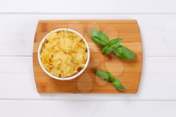 bowl of quadretti - square shaped pasta on wooden cutting board