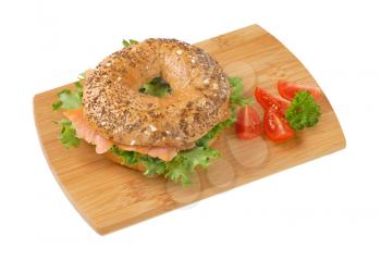 bagel sandwich with smoked salmon on wooden cutting board