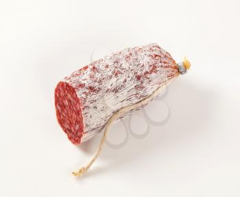 piece of French dry cured sausage on white background