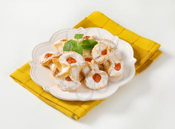 plate of cookies with apricot jam filling on yellow dishtowel
