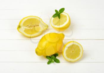 whole and halved lemons on white wooden background