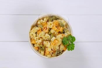 bowl of cooked colored pasta on white wooden background