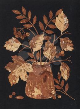 Manual job: bouquet from rowan leaves and berries, application from slices of a back of a birch bark on a black fabric