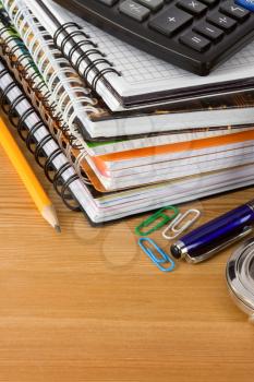 pile of notebook and pens on wood background texture