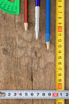 pencil and tape measure on wood texture