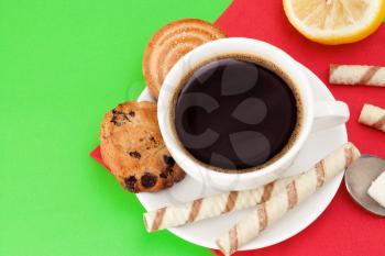 cup of coffee and cookies on green background