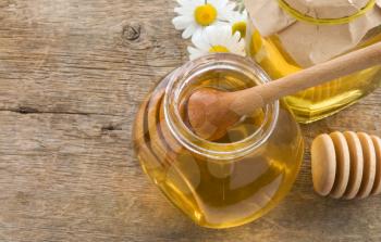 glass jar of honey and stick on wood background