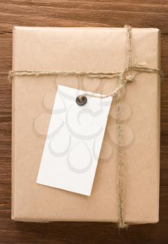 paper parcel wrapped tied with price tag on wood background