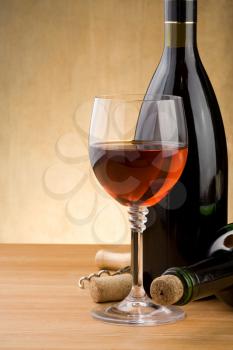 glass of red wine and bottle with grape on wood background