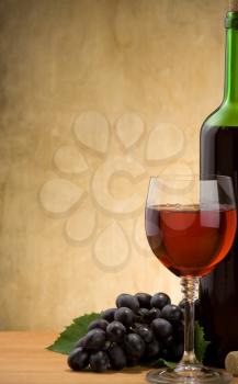 wine in glass and bottle with grape fruit on wood background