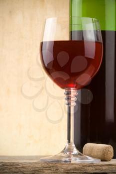 glass of red wine and bottle on wood background