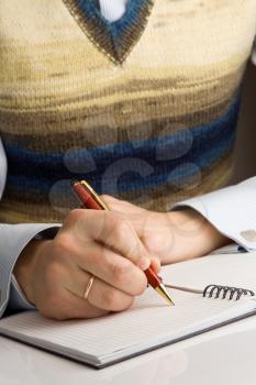 man writing by pen on checked notebook