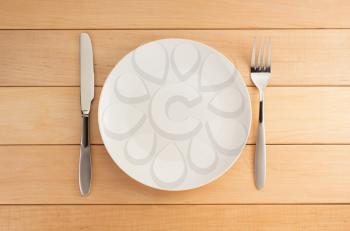 plate, knife and fork on wooden background