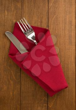 knife and fork at napkin on wooden background