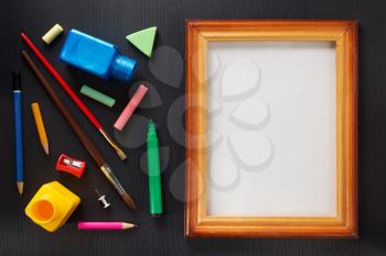 paint supplies and frame on black wooden background