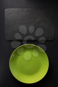black slate and plate оn wooden background