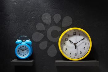 wall and alarm clock at black background texture