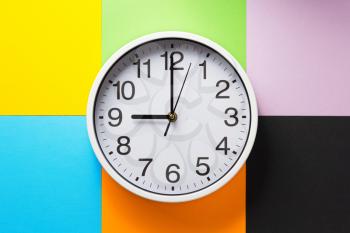 wall clock at abstract colorful paper background texture