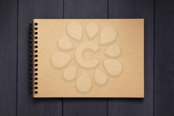 paper notebook at black wooden background surface table, top view